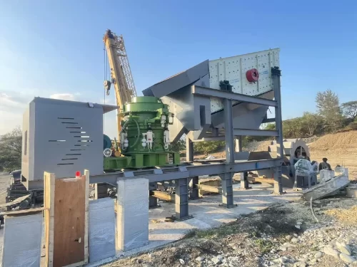 Heavy-duty gravel screening equipment working downstream from a rock grinder machine at an open-pit site.