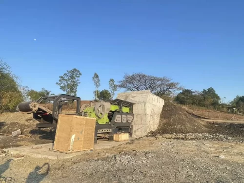 Heavy-duty gravel screening equipment working downstream from a rock grinder machine at an open-pit site.