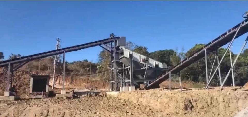 Heavy-duty gravel screening equipment working downstream from a rock grinder machine at an open-pit site.