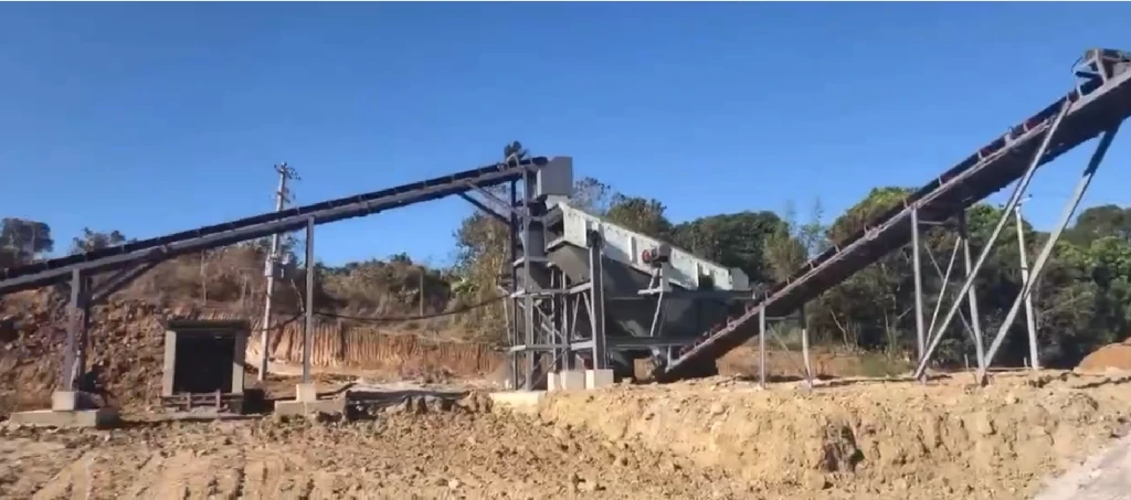 Heavy-duty gravel screening equipment working downstream from a rock grinder machine at an open-pit site.