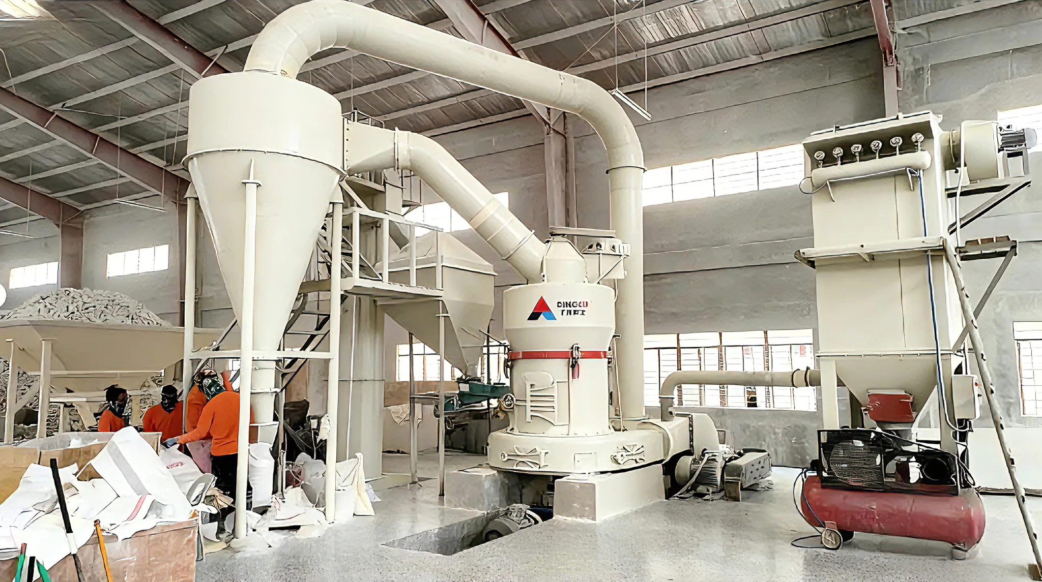 A row of heavy-duty aglime crushing equipment with fully enclosed chambers for dust control at the manufacturing facility.
